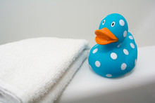 Cute Rubber Duck Beside A White Towel In A Bathroom