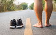 © SKT Studio - Legs of man with black running shoes on asphalt road in morning