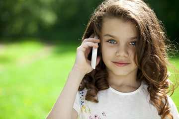 Wall Mural - Portrait of a beautiful young little girl calling by phone