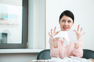 business woman sitting her desk getting rid of old papers with pleasure.