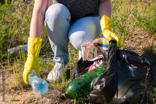 Fotografie, Obraz Volunteer girl in yellow gloves collects garbage selective focus