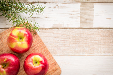 Healthy food: red apples and rosemary on wooden table