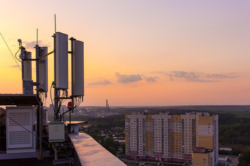 cellular communications tower on a background of the city and a beautiful sunset in summer