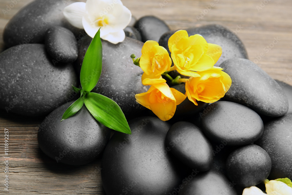 Beautiful spa composition with stones and freesia on wooden background