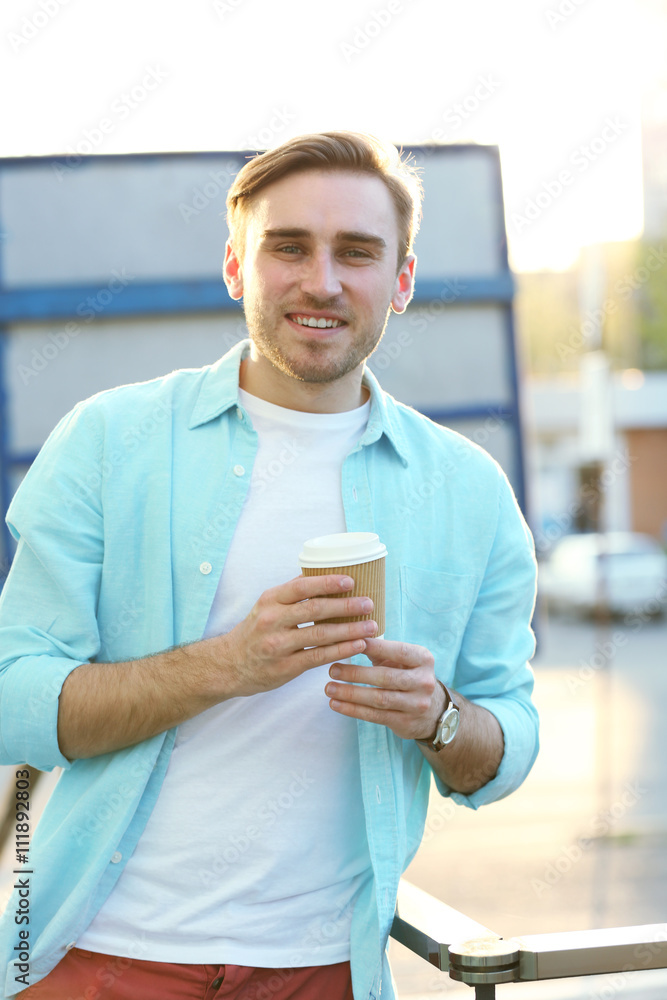 Young man with a cup of coffee outdoors