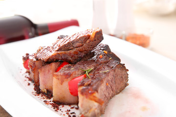 Wall Mural - Sliced roasted pork steak with bottle of red wine on white plate