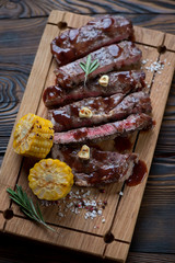 Wall Mural - Wooden serving board with sliced medium grilled rancho beefsteak