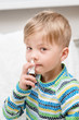 © Ermolaev Alexandr - ill boy with flu at home using nose spray