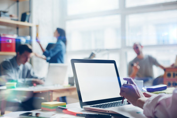 Fototapete - Young startup group working in loft office. Open space, digital and paperwork. Woman with laptop. Film effect, blurry background, lens flare effect