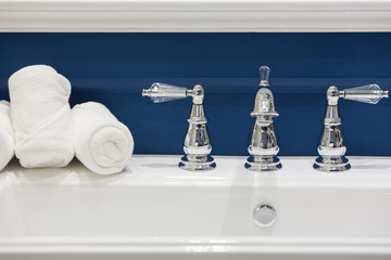 Three white hand towels on a white basin