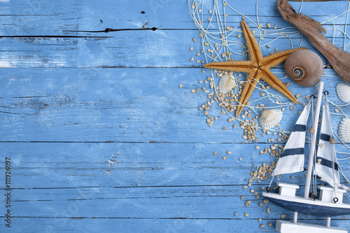 Fotografía Decoración marítima blauem auf Holzhintergrund mit Holzschiff, Seestern, Muschel