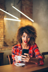 Wall Mural - Young woman at cafe drinking coffee and using mobile phone