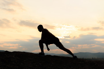 Beauty and sports concept. Silhouette of bodybuilder posing at sunset during his outdoor training