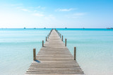 Fototapeta Do akwarium - Wooden bridge on the beach to the sea in blue summer sky.  Jetty