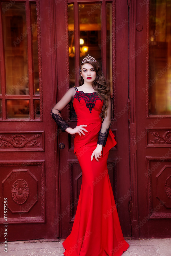 Beautiful young girl in a red evening long dress. The beauty queen in a red  dress with long hair and a tiara on her head Stock-foto | Adobe Stock
