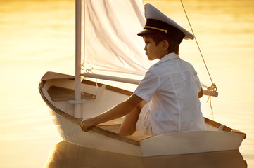 Boy floats on a boat with a sail