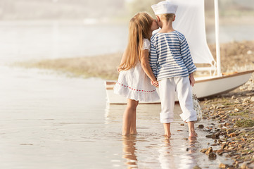 Boy with girl walking along the shore of the lake