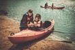 © Nejron Photo - Cheerful friends reading a map in kayaks on a beach.