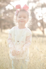 Wall Mural - Smiling baby girl 4-5 year old wearing stylish sweater outdoors. Looking at camera. Childhood. Summer time.