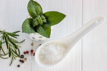 Sea salt scented herb rosemary and mint leaves on wooden backgro