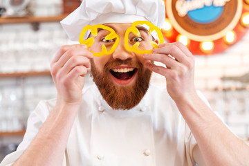 Wall Mural - Cheerful holding yellow bell pepper slices in front of eyes