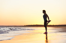 Woman Exercising On Beach At Sunset