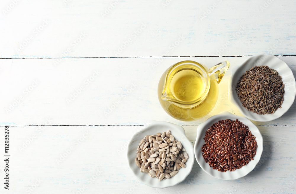 Different kinds of seeds and oil on wooden table
