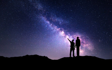 Wall Mural - milky way with silhouette of a family on the mountain. father and a son who pointing finger in night