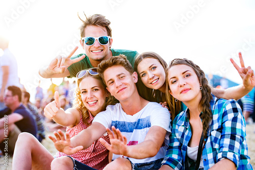 Valokuva Teenagers at summer music festival, sitting on the ground