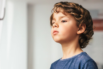 Cute little boy with curly hair looking away