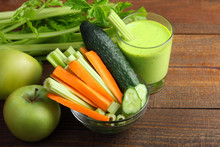 Fresh Green Celery And Cucumber With The Chopped Carrots In A Glass Bowl Near The Juice In A Glass And Green Apples On A Brown Wooden Background