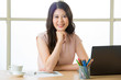 © PR Image Factory - Successful Asian female entrepreneur sitting and smiling at desk