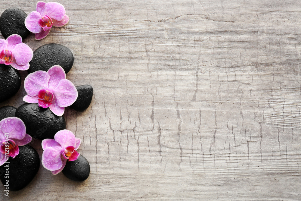 Spa stones and orchids on wooden background