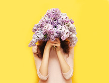 Woman Hiding Head In Bouquet Lilac Flowers Over Yellow Backgroun