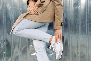 Clothing details: girl in a beige coat, jeans and sneakers outdo