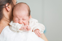 Newborn Baby Screaming In Pain With Colic On Mother's Shoulders