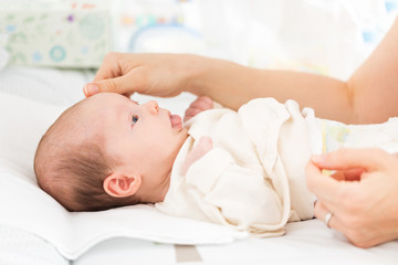 mother caressing her female newborn baby daughter while changing