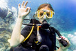 Frau beim Tauchen im Urlaub an Korallen Riff gibt das OK Zeichen