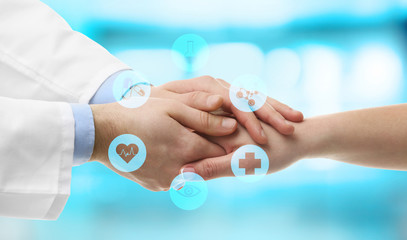 Poster - Male doctor holding patient's hand, on blurred background