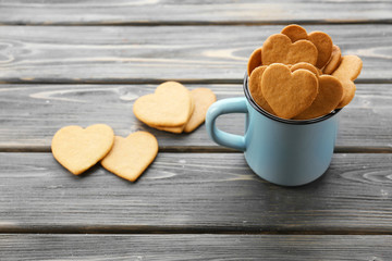 Wall Mural - Heart shaped biscuits in metal mug on wooden background