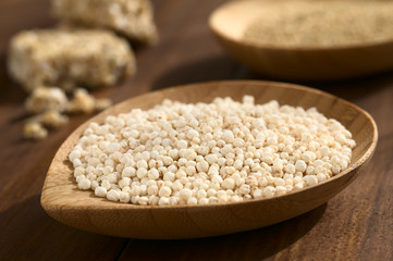 Wall Mural - Popped white quinoa (lat. Chenopodium quinoa) cereal on small wooden plate, photographed on wood with natural light (Selective Focus, Focus one third into the quinoa cereal)