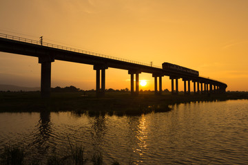 A train is crossing bridge at  Pa Sak Jolasid Dam, Thailand in sunset time