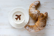 Aircraft made of cinnamon in cup of cappuccino and croissants