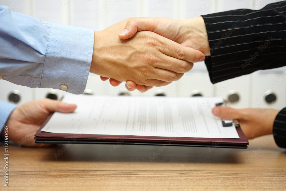 business partners are handshaking and exchanging contract after - obrazy, fototapety, plakaty 