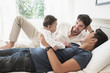 © JGI/Tom Grill/Blend Images - Gay fathers playing with baby son on bed