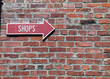 Red Arrow Sign on a Red Brick Wall Pointing to Shops
