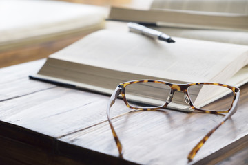 Wall Mural - glasses on opening book in library or cafe