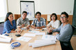 © DragonImages - Asian business team sitting at big table at looking at camera