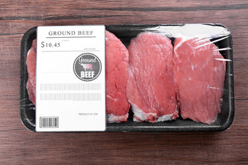 Poster - Packed pieces of beef meat on wooden background