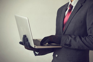 Business man wearing gloves and using computer - fraud, hacker, theft, cyber crime concept